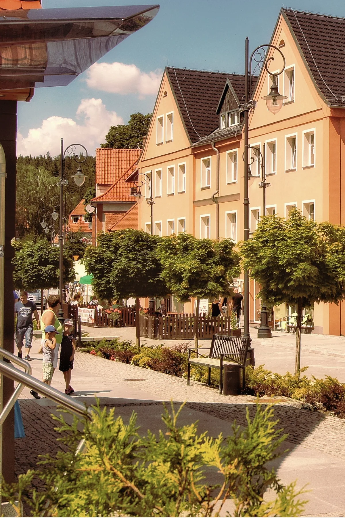 Begrünte Fußgängerzone mit Sitzbank und Passantinnen und Passanten