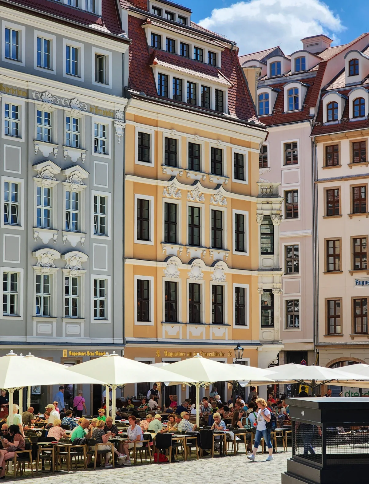 Belebter Stadtplatz mit Außengastronomie vor historischen Innenstadtgebäuden
